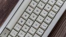 Load image into Gallery viewer, GMK MTNU Beige keycaps on white 65% keyboard, front profile view showing keycap height and sculpt on dark wood