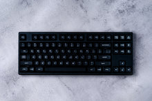 Load image into Gallery viewer, GMK MTNU WoB black keycaps on white 65% keyboard, top-down view on dark wood surface
