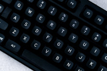 Load image into Gallery viewer, GMK MTNU WoB black keycaps on white 65% keyboard, wide angle lifestyle shot on dark wood