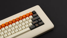 Load image into Gallery viewer, GMK CYL Carbon R3 on a cream colored keyboard close up on right side angled