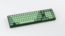 Load image into Gallery viewer, GMK CYL Zooted keycaps on dark green full-size keyboard, top-down angled shot showing complete layout with numpad and mint green alphas with darker green modifiers on white surface