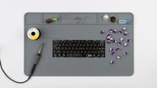 Load image into Gallery viewer, Silicone Project Mat with soldering iron, keycap puller, a PCB, switches, lubricant, screws, and other items on it.