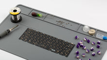 Load image into Gallery viewer, Silicone Project Mat with soldering iron, keycap puller, a PCB, switches, lubricant, screws, and other items on it - angled.