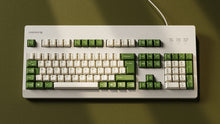 Load image into Gallery viewer, Render of DCS Cream Cheese R3 keycaps on silver keyboard, wide angle showing full layout