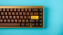 Load image into Gallery viewer, Render of GMK CYL Chocolatier keycaps on a cream keyboard, angled view highlighting the golden yellow accent keys