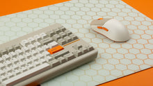 Load image into Gallery viewer, NovelKeys Glasspad under a beige Classic TKL keyboard and NK-M1 mouse on an orange background