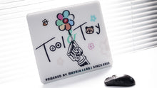 Load image into Gallery viewer, Matrix MP-01 glass mouse pad standing upright beside a black mouse, showing the Tool &amp; Toy design